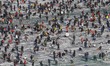 Visitors cast lines through holes drilled in the surface of a frozen river during a trout...