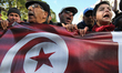 People hold Tunisian flag as they chant slogans during the celebration of the 7th annivers...