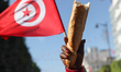 A breadstick and a Tunisian flag are raised during the celebration of the 7h anniversary o...