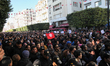 People hold Tunisian flags as they chant slogans during the celebration of the 7th anniver...