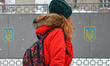 A lady passes in front of the gate with Ukrainian coat of arms, in Lviv's city center. On...