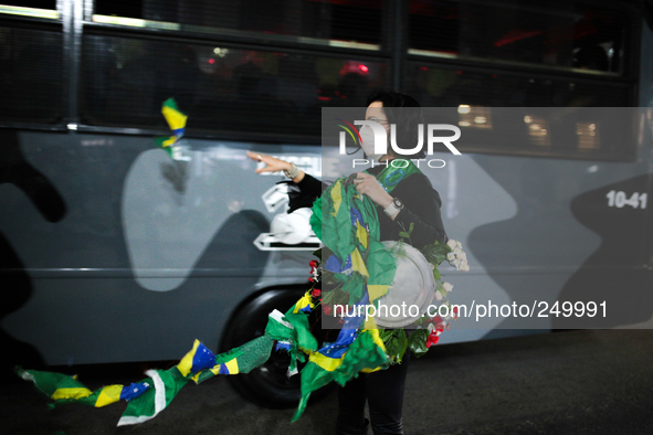 A woman rips a Brazilian flag while a riot police bus pass by after an eviction ended in violent clashes in downtown Sao Paulo, Brazil on Se...