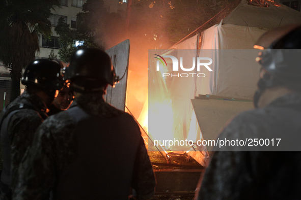 Riot police observe a tent catching fire in the middle of a square after an eviction ended in violent clashes in downtown Sao Paulo, Brazil...