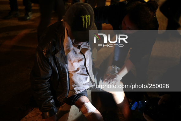 Rescuers succor a man who was wounded in the leg by rubber bullets fired by police after an eviction ended in violent clashes in downtown Sa...