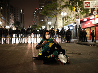 A woman rips a Brazilian flag in front of a line of riot police after an eviction ended in violent clashes in downtown Sao Paulo, Brazil on...
