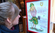 A lady looks at the caricature of the US President Donald Trump dressed as St Patrick hold...