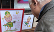 A man looks at the caricature of the US President Donald Trump dressed as St Patrick holdi...