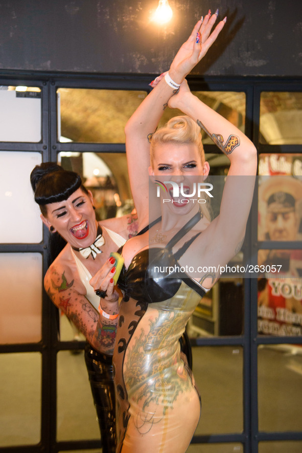 The 10th International London Tattoo Convention on 26/09/2014 at Tobacco Dock, London. 2 latex clad models shine their outfits before a phot...