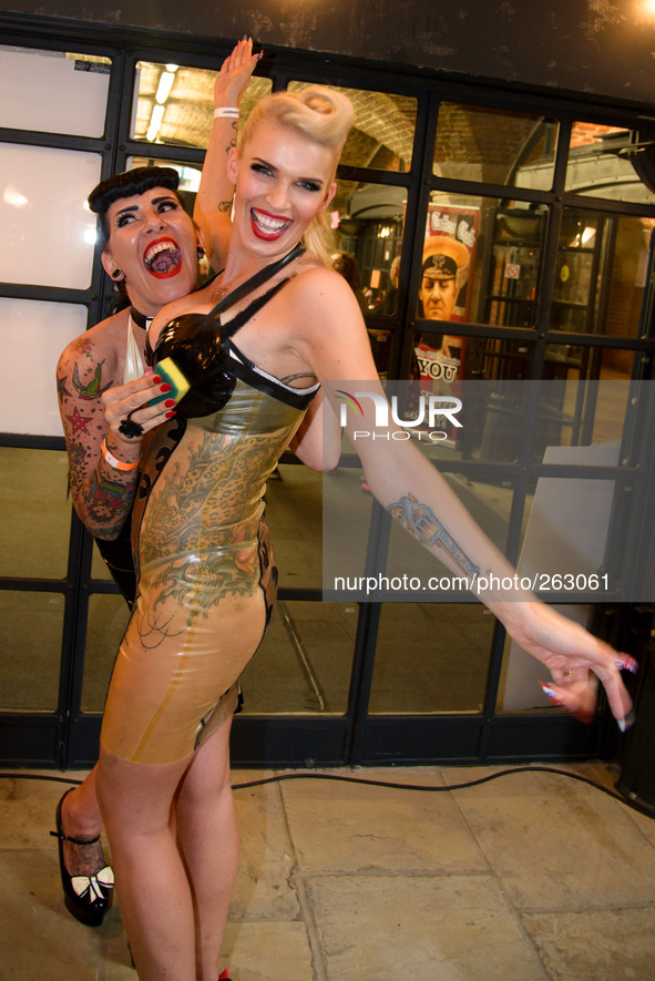The 10th International London Tattoo Convention on 26/09/2014 at Tobacco Dock, London. 2 latex clad models shine their outfits before a phot...