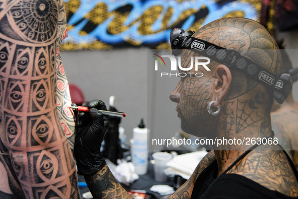 The 10th International London Tattoo Convention on 26/09/2014 at Tobacco Dock, London. A fully tattooed artist draws on the body of his subj...