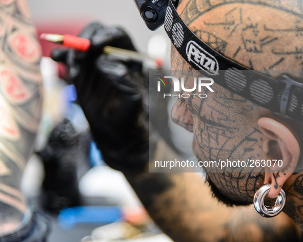 The 10th International London Tattoo Convention on 26/09/2014 at Tobacco Dock, London. A fully tattooed artist draws on the body of his subj...