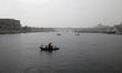 Bangladeshi commuters cross on the Buringanga River by small wooden boat during the heavy...