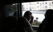 52 year-old Andres Gonzalez Manzano (middle) looks through the window and gestures as he w...