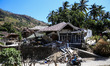 People ride motorcycle along next to collapsed house after an earthquake hit on Sunday in...