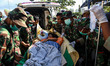 Indonesian police and soldiers evacuate a woman after arriving at Tanjung hospital after e...