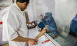 Laboratory manager Hekmatullah Sadat draws blood of woman wearing burka for blood test in...
