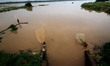 Villagers are seen on the banks of flooded river Kuakhai as they catch fish into the flood...