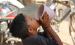 A boy drinks water from a jug outside Chawri Bazar metro station in Old Delhi, India, on 6...
