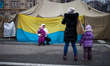 Woman takes pictures of herself and her child near a anti protester tent in maidan square...