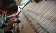 Woman weaves the silk carpet with Afghan royal pattern and 80 knots per centimetre at the...