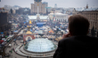 A man at his balcony watches people take part in a mass rally on Independence square in Ki...