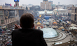 A man at his balcony watches people take part in a mass rally on Independence square in Ki...