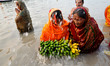 Indian Hindu devotees perform rituals during Chhat Puja while standing in the river in Kol...