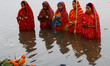Indian women devotees look inside the river water as they offer rituals to Sun God on the...
