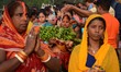 Indian Hindu women devotees offering prayers to the Sun God on the banks of river Ganges i...