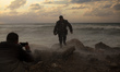 A Palestinian man picks up a picture of his friend on the shore of the sea in Gaza City, w...