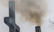 Smoking chimney of the coal stove in front of Catholic cross is seen in Gdynia, Poland on...
