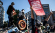 Protesters, one wearing a gas mask, hold signs near a destroyed vehicle in Taksim Square,...