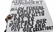 Furloughed federal workers, joined by elected officials, hold up sings to protest the fede...