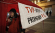 A half dozen people are seen gathered in front of the state broadcaster TVP Info headquart...