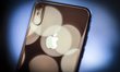 The Apple logo and it's camera are seen on the back of an iPhone X in this photo illustrat...