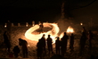 Participants perform a fire dance and create a fire ring by swing bales of burning straw d...