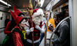 Santa Claus and his Elfs take a look at a woman's gift on a subway train in Sao Paulo, Bra...