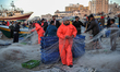 Palestinian fishermen pull their nets as they collect fish at the seaport in Gaza city on...