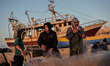 Palestinian fishermen pull their nets as they collect fish at the seaport in Gaza city on...