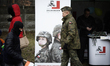 A man in a military uniform walks past a recruitment poster for defence personnel in Bydgo...