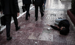 A beggar lies on a pavement as businessmen with briefcases walk past him in Athens on Nove...