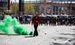 A protester walking in front of police officers while a bengal is burning  during a Vox pa...