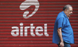 A man walks past in front of  a shop painted with an advertisement of India’s telecom gian...