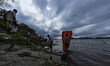 Fish vendor work on the bank of the Brahmaputra river as rain clouds gather over Guwahati...