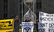Extinction Rebellion eco activists stands near sandglass art instalation during disrupt Wa...