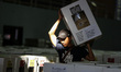 Workers carry ballot boxes for distribution to the polling stations in a warehouse in Jaka...