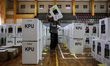 Workers carry ballot boxes for distribution to the polling stations in a warehouse in Jaka...