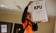 Workers carry ballot boxes for distribution to the polling stations in a warehouse in Jaka...