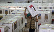 Workers carry ballot boxes for distribution to the polling stations in a warehouse in Jaka...