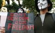 A protester wearing a Guy Fawkes mask carrying a poster against the alleged constriction o...